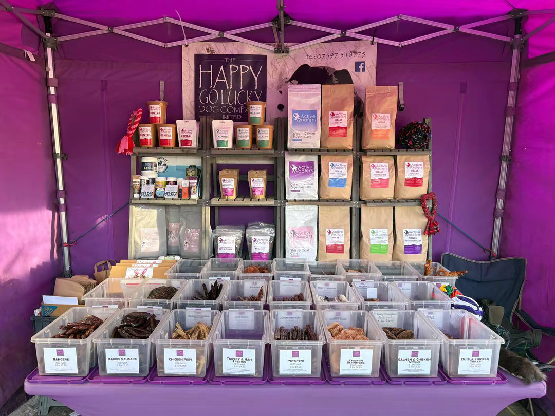 Product display under a purple tent with 'Happy Go Lucky Dog Company' and ‘Active Woofers’ branding.